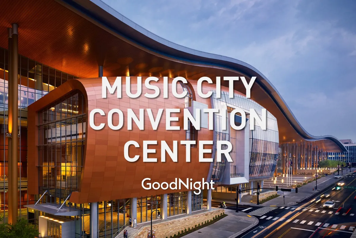 A modern, curved building with large glass windows illuminated by dynamic signage. The entrance bustles with activity, suggesting a major conference or event, perfectly capturing the energetic and welcoming vibe of Nashville’s business venues.