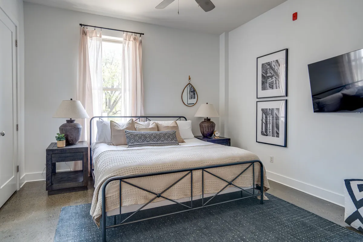 A serene bedroom with a luxurious king-size bed, complemented by elegant nightstands, a soft lamp glow, and tasteful artwork. The space exudes calm with a soothing color palette and minimal yet refined décor, inviting rest and comfort.
