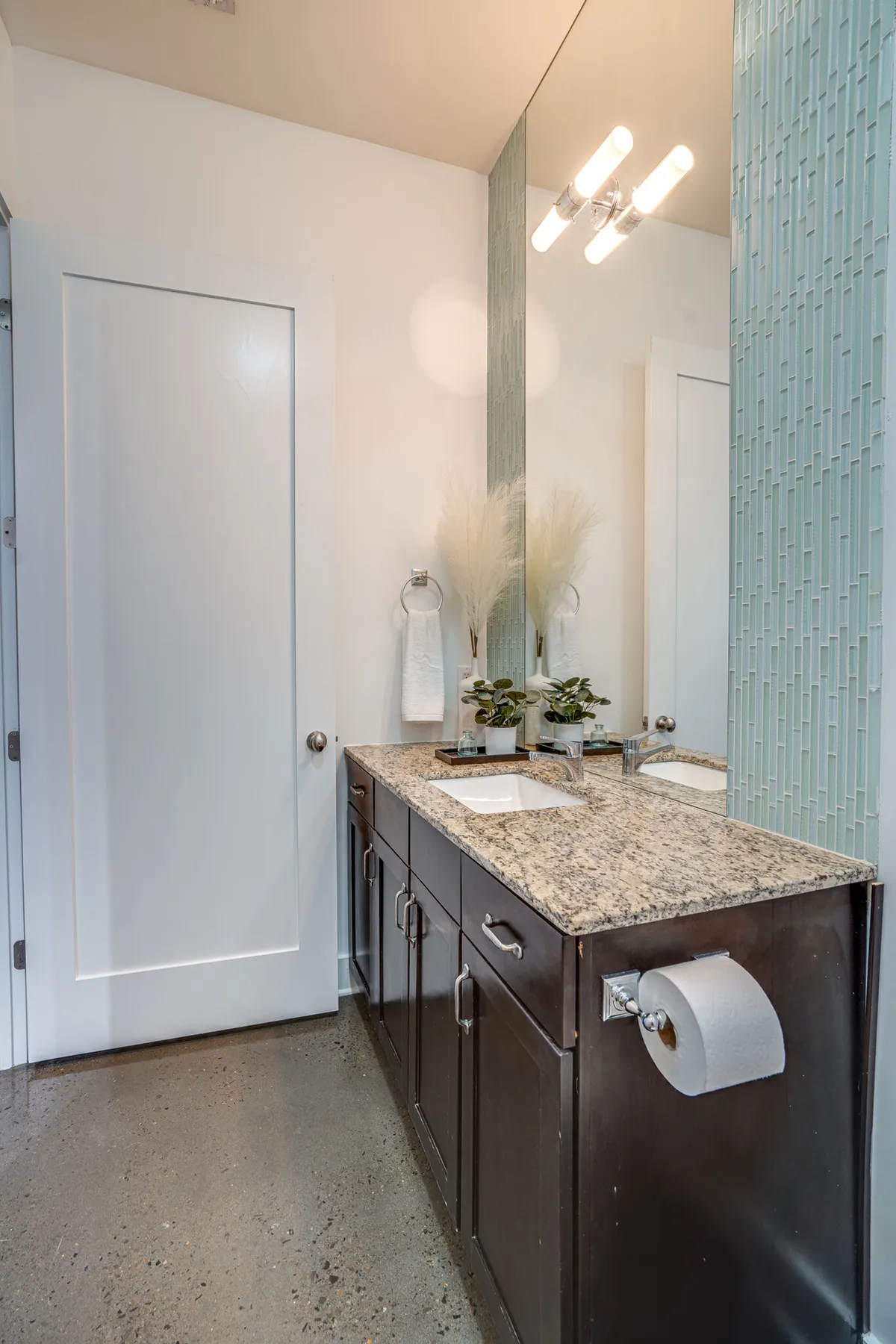 A spa-inspired bathroom with modern granite countertops, elegant lighting fixtures, textured wall tiles, and decorative plants. The space feels serene and inviting, perfect for self-care routines and luxurious moments of relaxation.